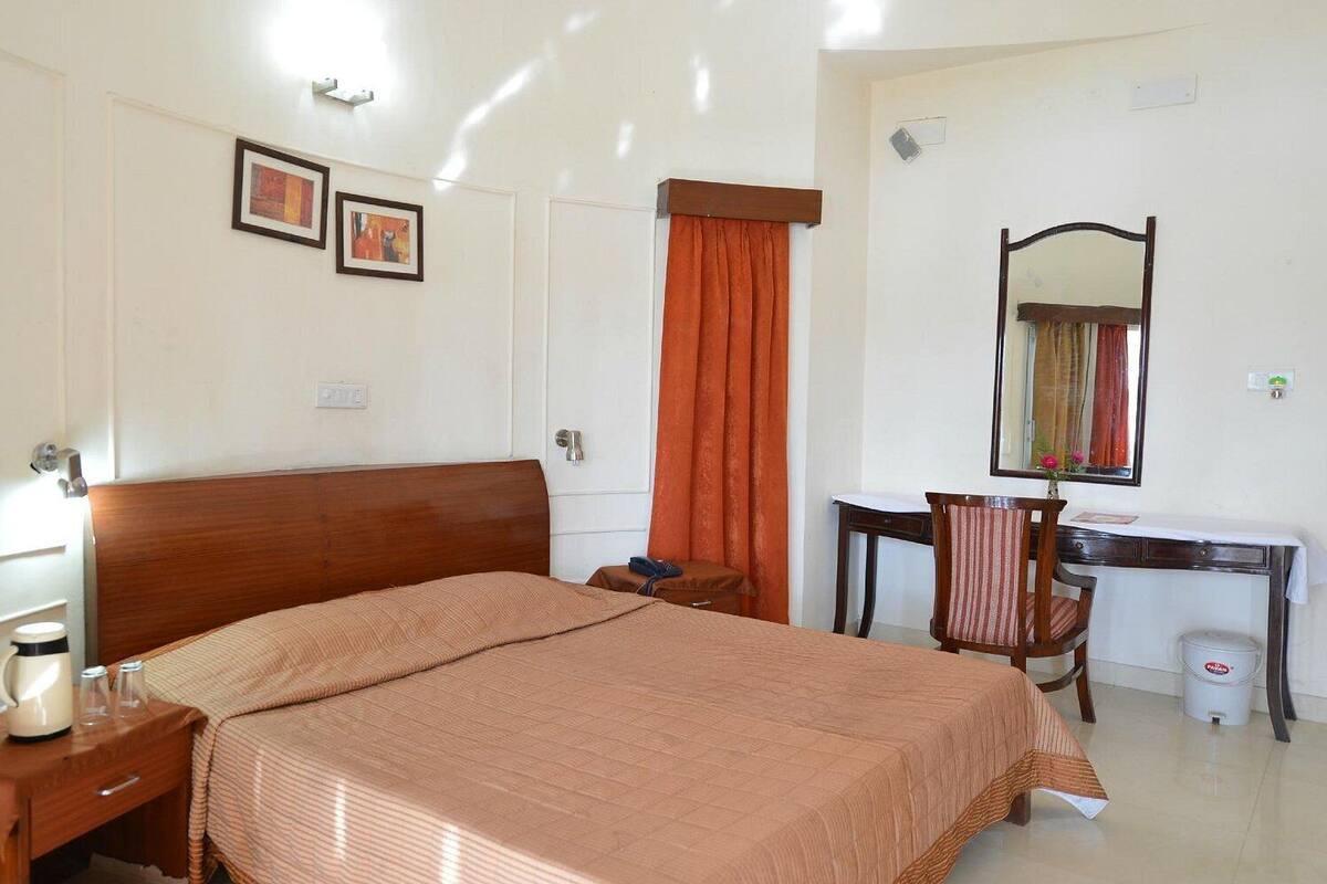 Una habitación de hotel con una cama grande, un escritorio, una silla y un espejo.