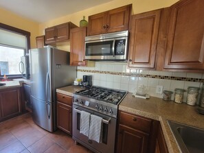 Equipped with a refrigerator, microwave, and gas stove, this kitchen offers ample space for cooking and storage.