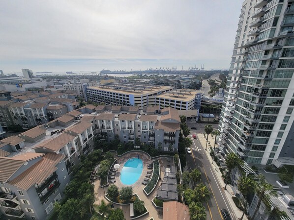 Residents enjoy a central pool surrounded by lush greenery and palm trees, with balconies and terraces offering outdoor space.