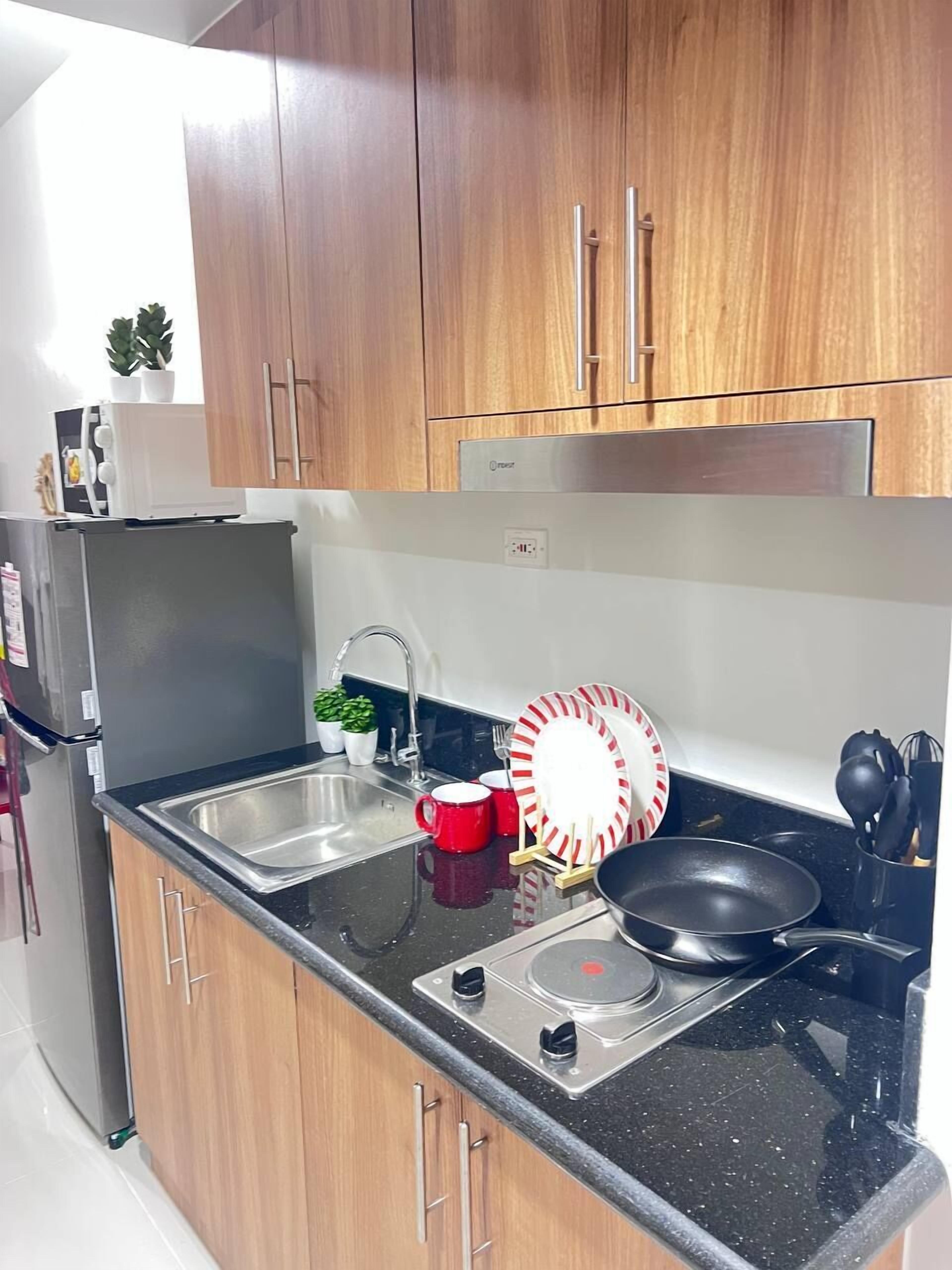 A modern kitchen with wooden cabinets, a stainless steel refrigerator, a sink, and a stove.