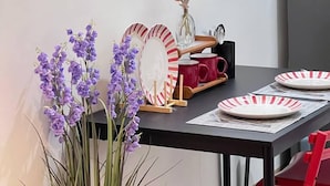 A dining area with a table set for two, featuring striped plates, a vase with flowers, and a mirror on the wall. - 10th floor (Pasay)