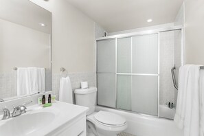 A modern bathroom with a white sink, toilet, and bathtub. - Bay Harbor Sunset Apt 5B (Bay Harbor Islands)