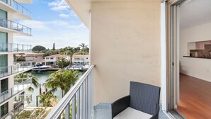 A balcony with a view of a marina, a dining area with a kitchen, and a pool. - Bay Harbor Sunset Apt 5B (Bay Harbor Islands)