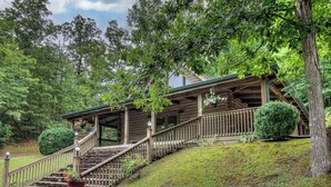 A wooden cabin with a porch, stairs, and a small garden. - Cozy 2-bedroom cabin in welcoming lake Douglas, Sevierville near Pigeon Forge (Sevierville)