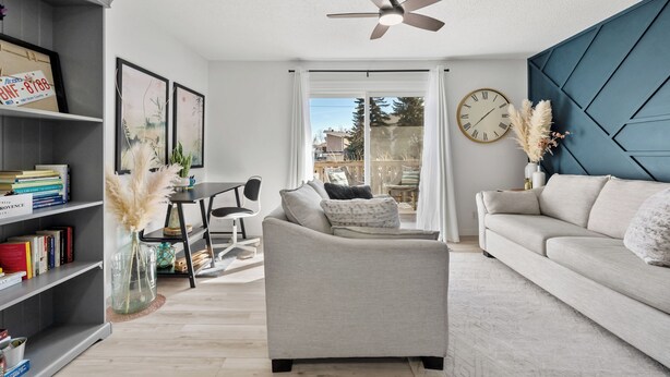 A modern living room with a sofa, a coffee table, a bookshelf, and a ceiling fan. - Charming 2-bedroom condo central NW (Calgary)