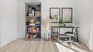 A modern room with a grey bookshelf, a desk with a chair, and two framed artworks on the wall. - Charming 2-bedroom condo central NW (Calgary)