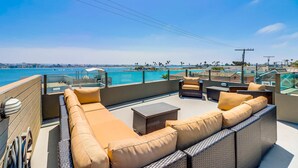 A rooftop terrace with a view of the ocean, furnished with a sofa and a table. - Single Family Retreat | Steps to Bay & Beach | Fireworks Views (San Diego)