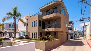 A modern multi-story building with balconies, a landscaped garden, and a clear sky. - Single Family Retreat | Steps to Bay & Beach | Fireworks Views (San Diego)
