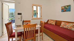A room with a wooden table and chairs, a red sofa, a window with a view, and a painting on the wall. - Stella Marina Apartment 6, Vieste, Italy (Vieste)