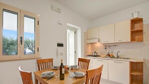 Une cuisine moderne avec des meubles blancs, une table à manger dressée pour quatre personnes et une vue sur l’extérieur.