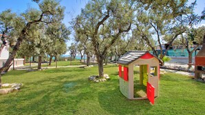 Une maison de jeu pour enfants dans un parc, avec des arbres et un ciel dégagé.