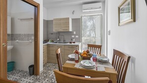 Une cuisine compacte équipée d’un évier, de placards et d’un coin repas avec des chaises et une table dressée pour deux personnes.