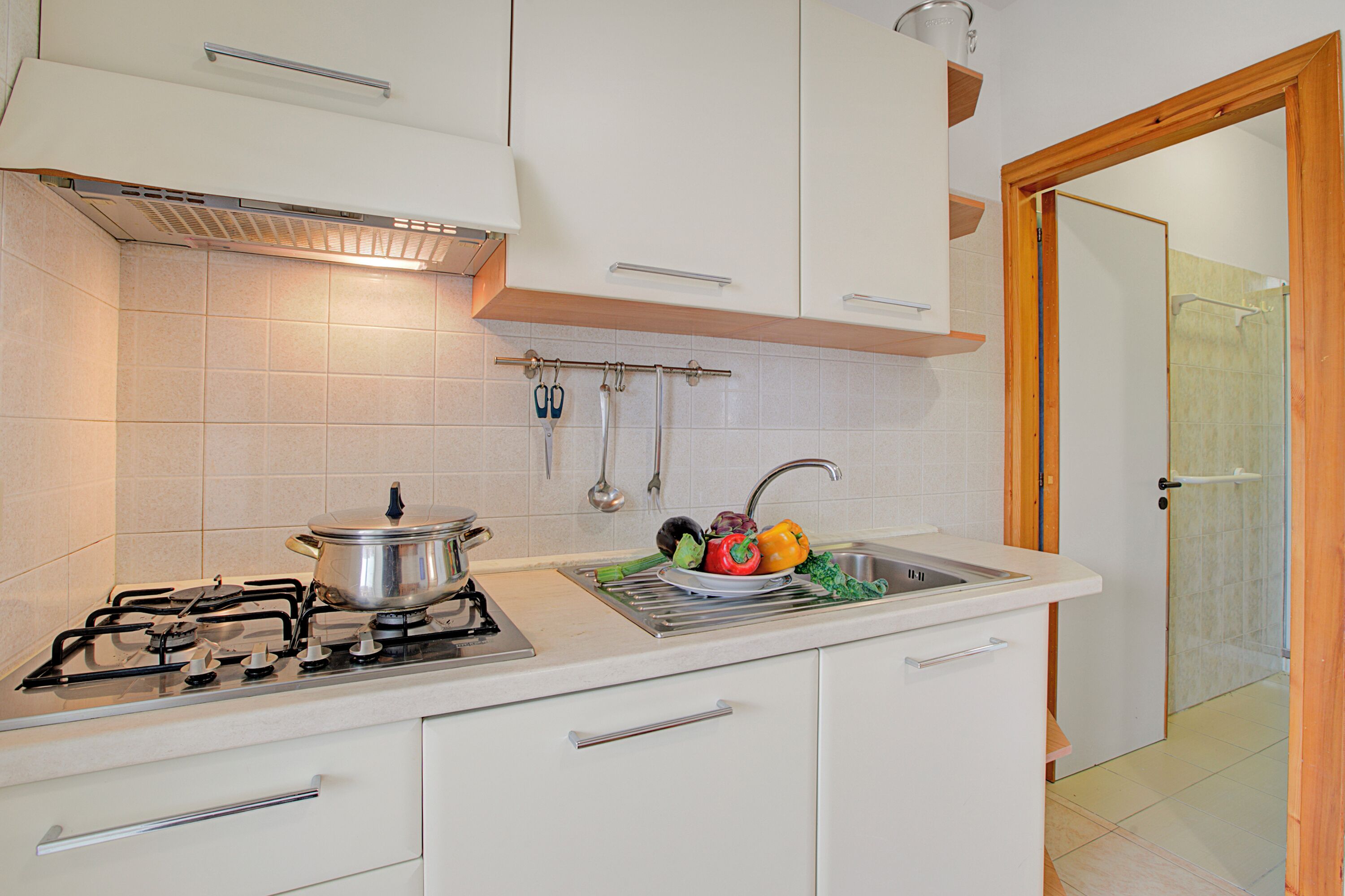 Una cocina con armarios blancos, estufa y lavamanos.
