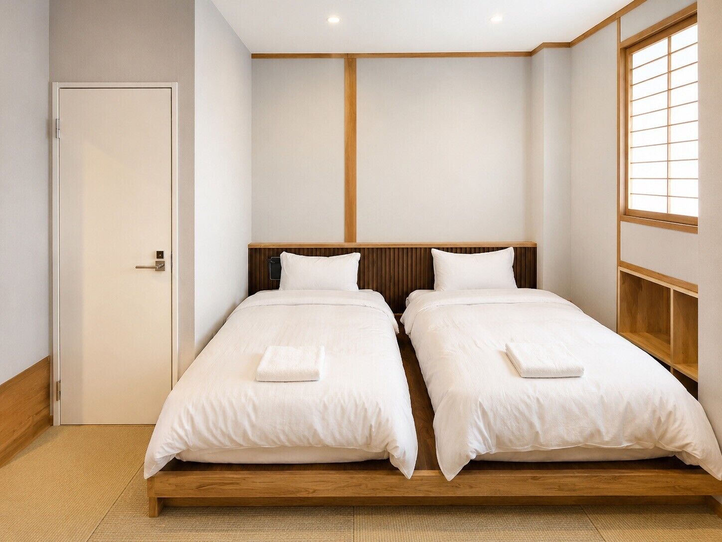 A room with two beds, a wooden headboard, a door, and a window with a grid pattern.