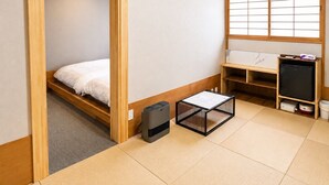 A room with a bed, a small table, a heater, a window with shoji screens, and a wooden cabinet. - ZaoSunvalley Hotel (Yamagata)