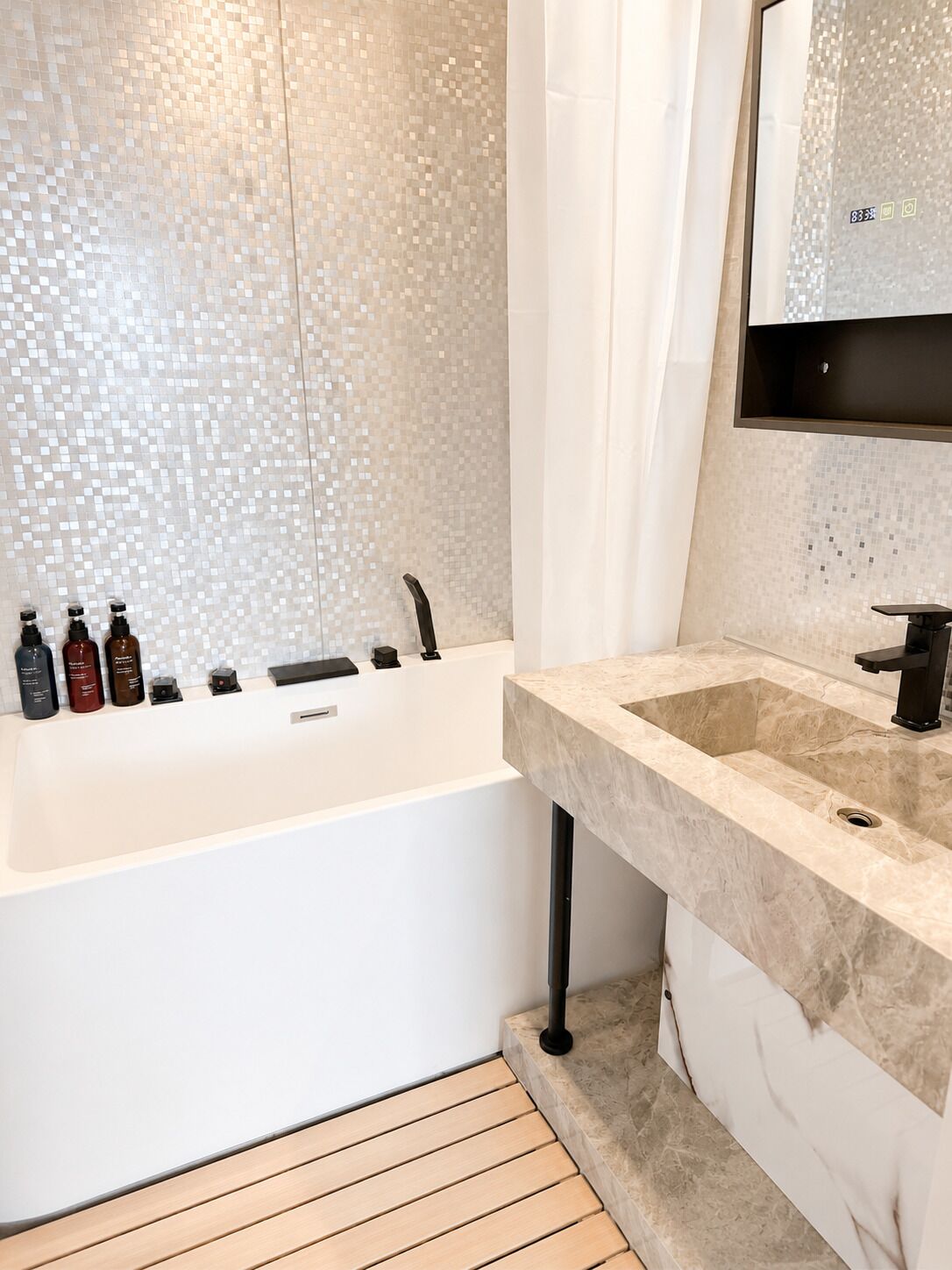 A modern bathroom with a bathtub, a sink, and a mirror.