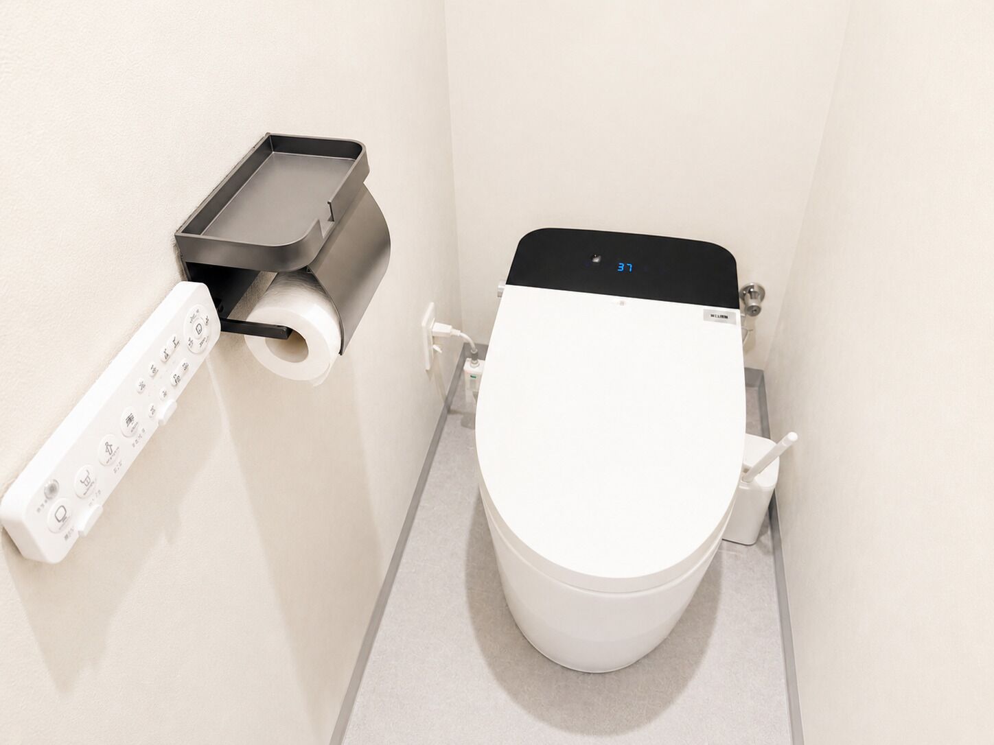 Un inodoro moderno con pantalla digital, dispensador de papel higiénico y panel de control de bidé.