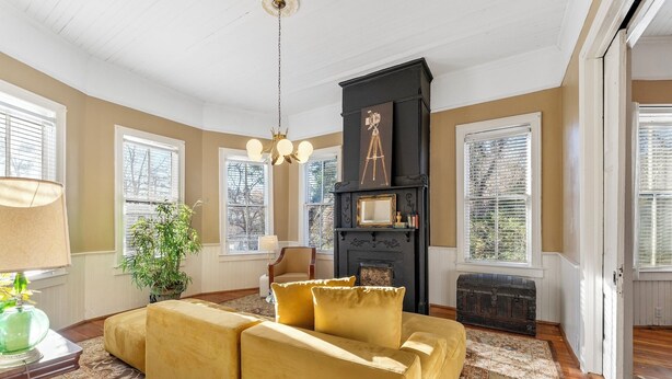 A living room with a yellow sofa, a fireplace, and a large window.