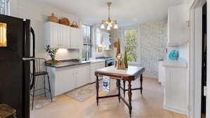 A kitchen with white cabinets, a wooden dining table, and a chandelier.