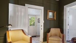 A room with two armchairs, a mirror, and a door leading to a balcony.