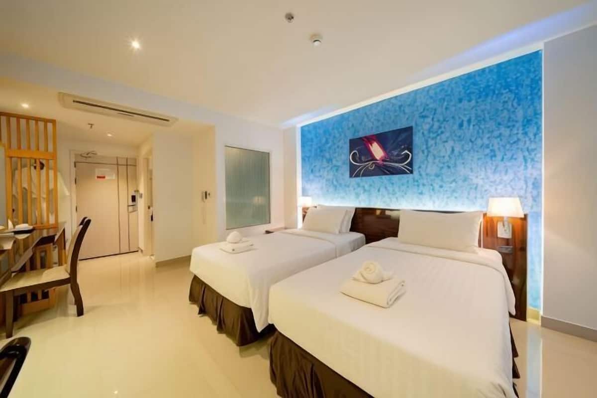 Ein Hotelzimmer mit zwei Betten, einem Schreibtisch und einem Stuhl.
