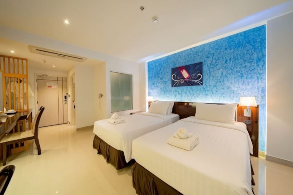 Habitación de hotel con dos camas, un escritorio y una silla.
