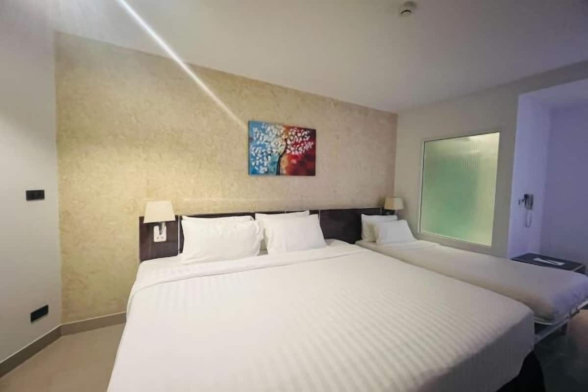 Ein Hotelzimmer mit einem großen Bett, zwei Nachttischen, einem Bild an der Wand und einem Fenster.