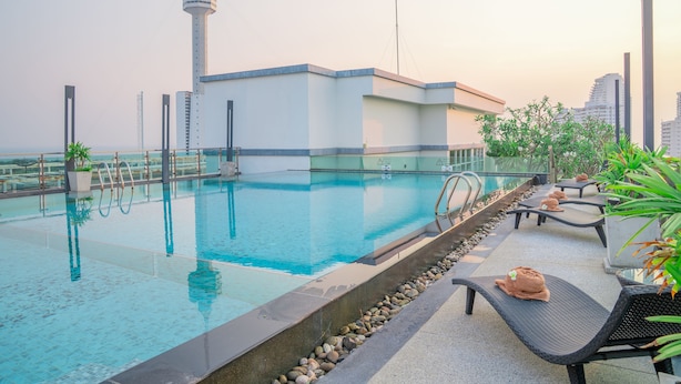 A rooftop swimming pool with lounge chairs and a view of a tower. - Royal Prince Resort Pattaya (Pattaya)