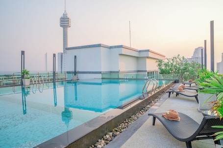 A rooftop swimming pool with lounge chairs and a view of a tower.