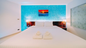 A hotel room with a large bed, two bedside lamps, a painting on the wall, and a floral-patterned wall hanging. - Royal Prince Resort Pattaya (Pattaya)