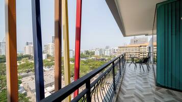 A balcony with a view of a cityscape, featuring buildings and greenery.