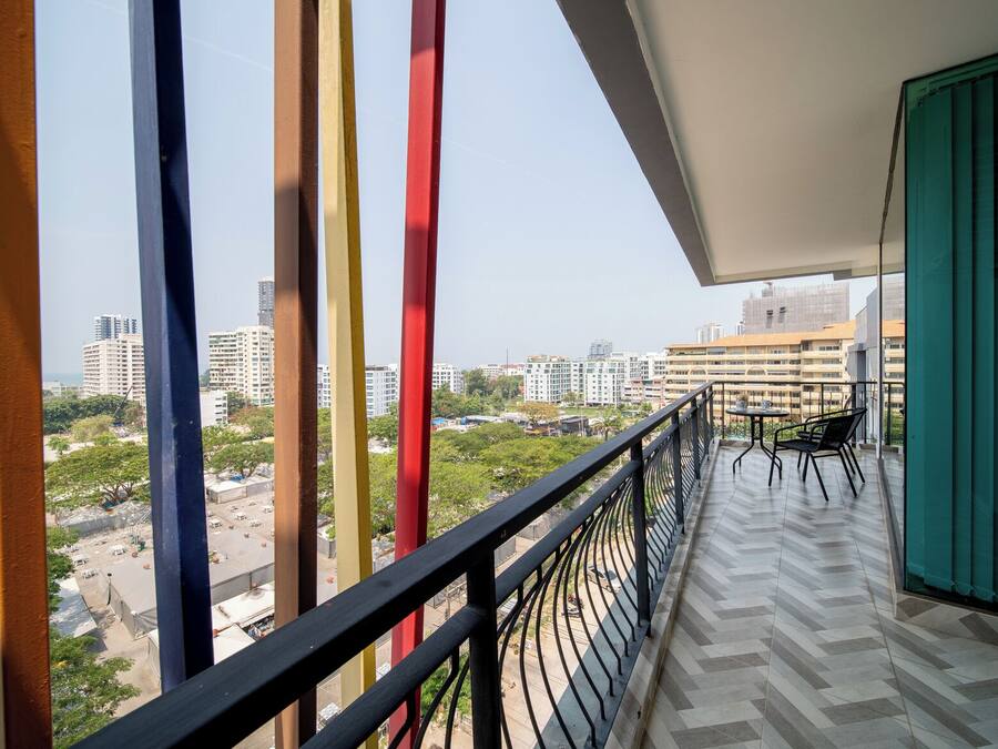 A balcony with a view of a cityscape, featuring buildings and greenery.