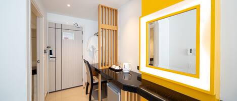 Una habitación de hotel moderna con área de cocina, una mesa de comedor y un espejo grande con marco amarillo.