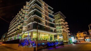 A multi-story hotel with balconies, a covered entrance, and decorative lights. - Royal Prince Resort Pattaya (Pattaya)