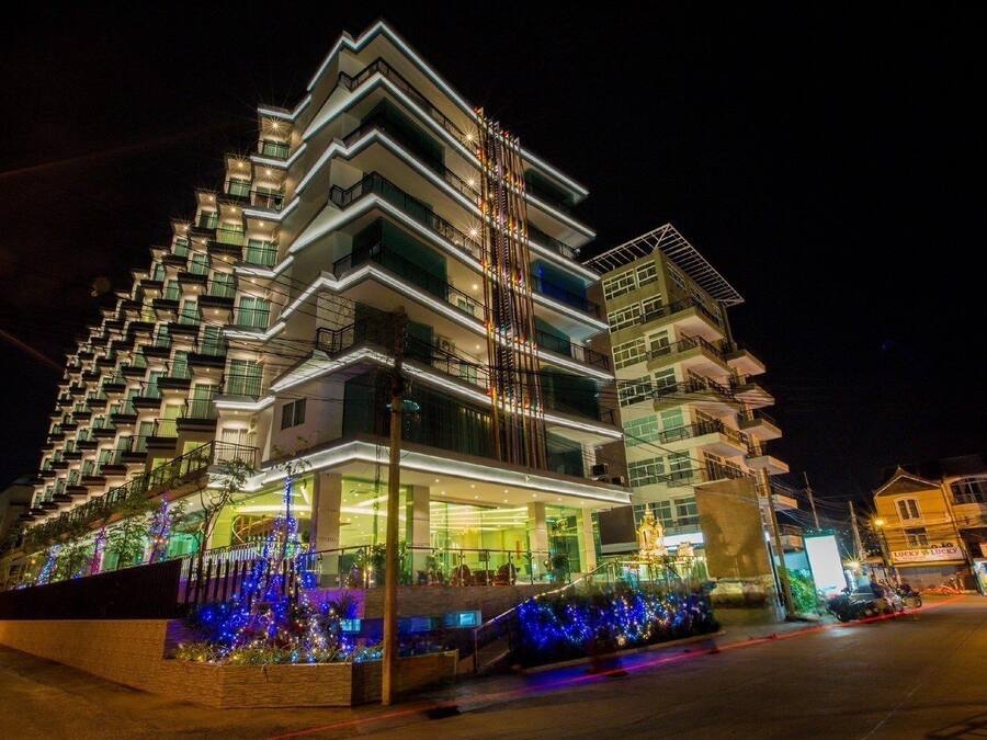 Un hotel de varios pisos con balcones, una entrada cubierta y luces decorativas.
