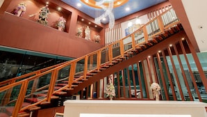 A modern hotel lobby with a wooden staircase, a central chandelier, and a reception desk. - Royal Prince Resort Pattaya (Pattaya)