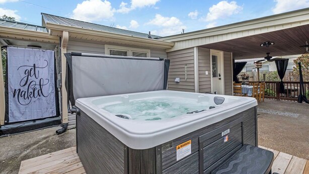 Un jacuzzi en un patio trasero con un porche techado.