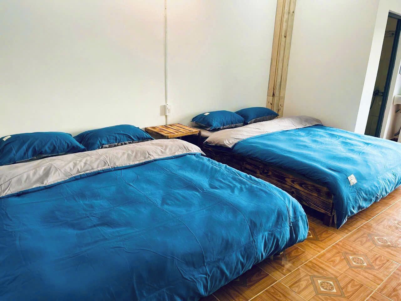 Een kamer met twee bedden, elk voorzien van blauw beddengoed en een houten hoofdbord.