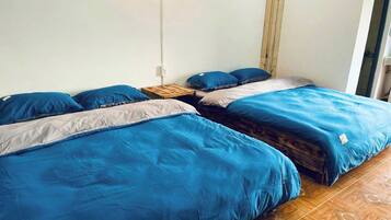 Een kamer met twee bedden, elk voorzien van blauw beddengoed en een houten hoofdbord.