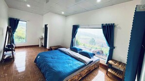 A bedroom with a large bed, a view of the outdoors, and a wooden floor. - Gió Homestay – Măng Đen (Mang Den)