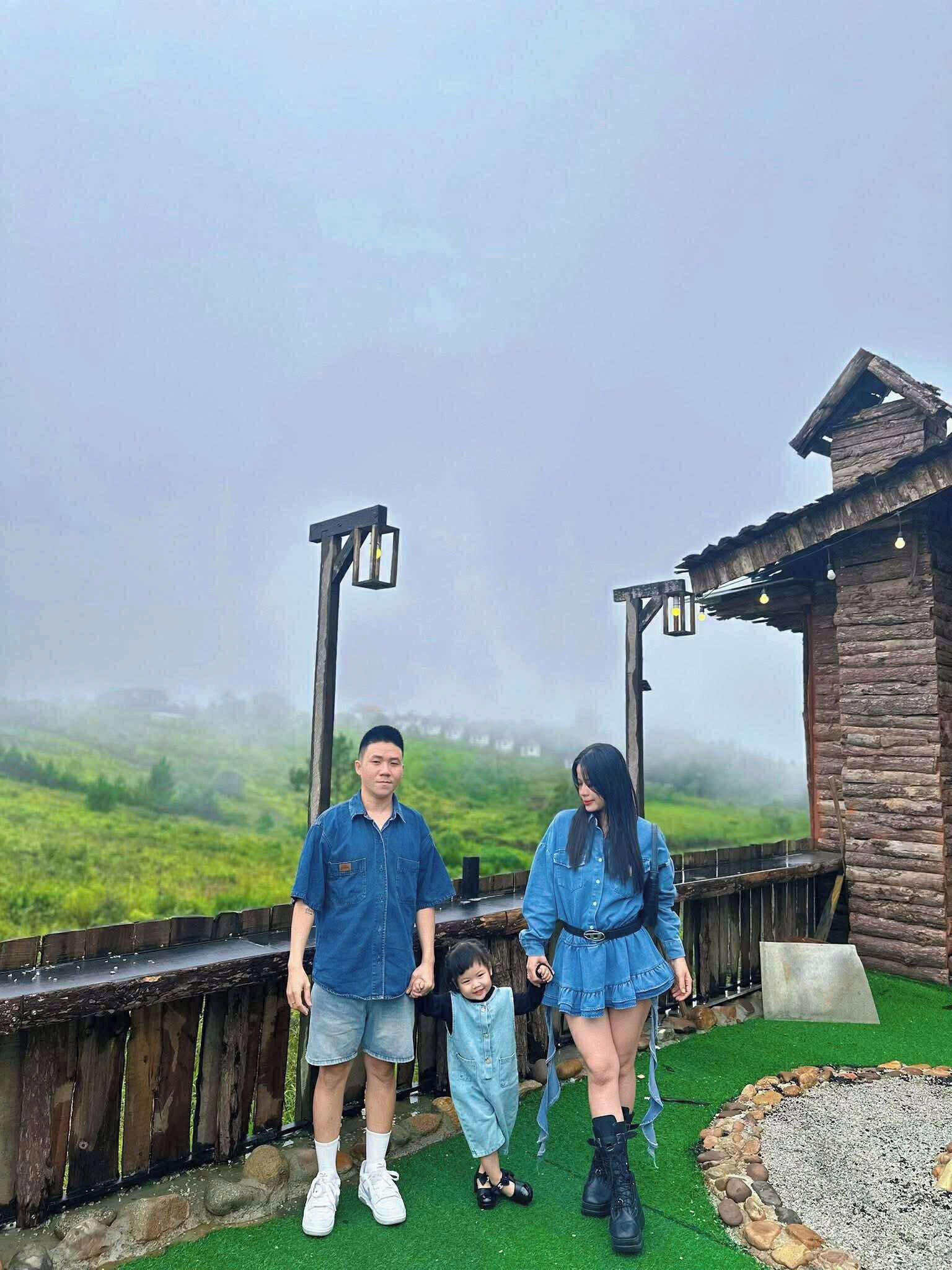 A rustic wooden cabin with a thatched roof, a stone pathway, and a view of a green landscape.