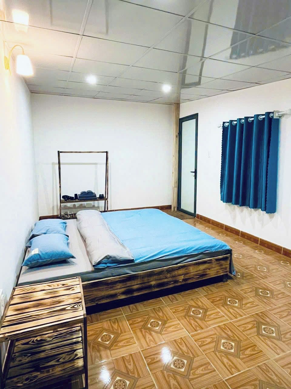 Ein Schlafzimmer mit Holzboden, einem Bett mit blauer Bettwäsche, einem kleinen Tisch und einem Spiegel an der Wand.