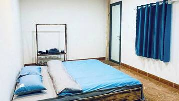 Ein Schlafzimmer mit Holzboden, einem Bett mit blauer Bettwäsche, einem kleinen Tisch und einem Spiegel an der Wand.