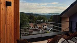 Ein Balkon mit Holzbalkonen, Blick auf einen Berg und eine Wohngegend im Hintergrund.