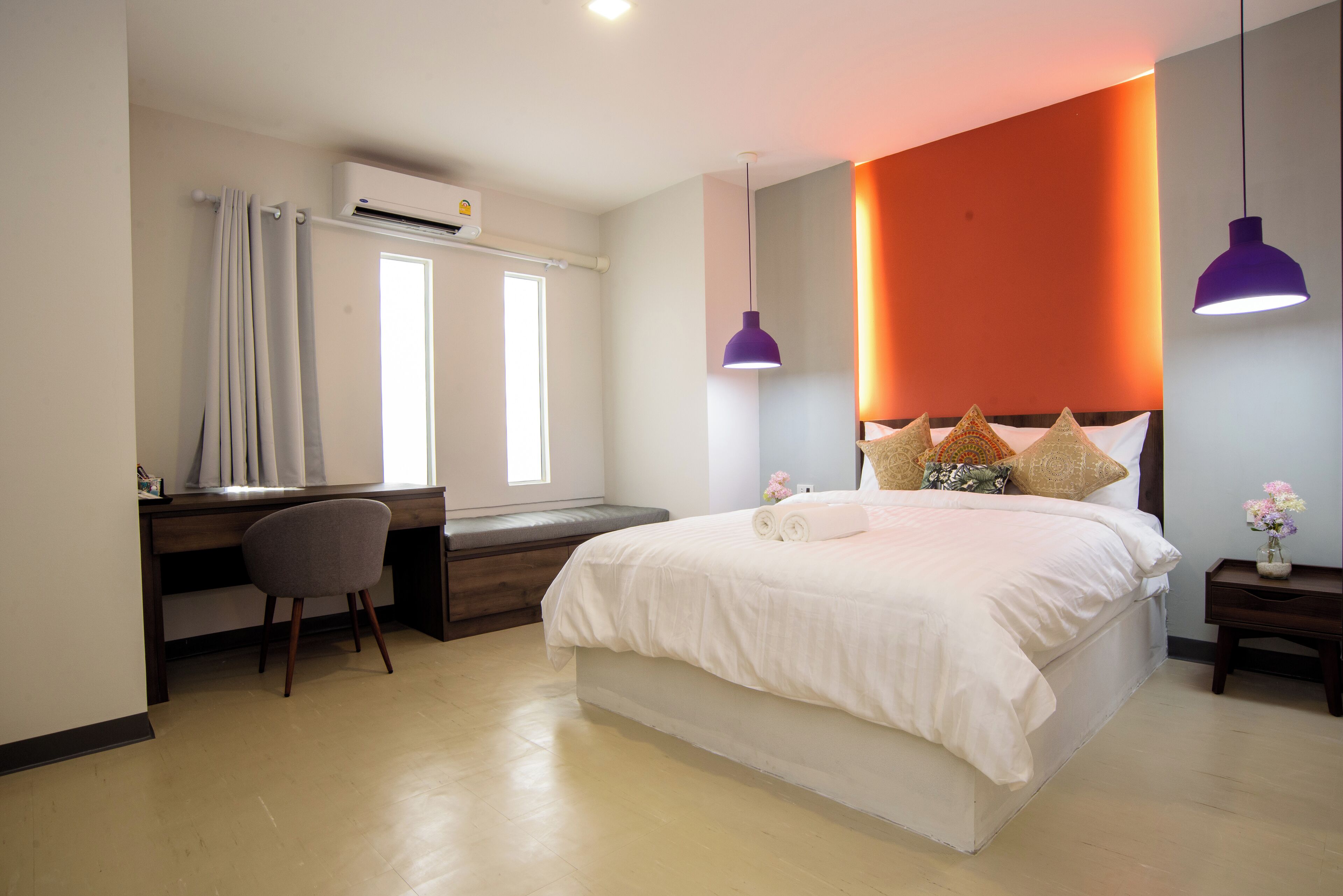 Un dormitorio con cama, escritorio, silla y mesitas de noche.