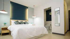 Un dormitorio moderno con una cama grande, mesitas de noche, un espejo y vistas al baño.