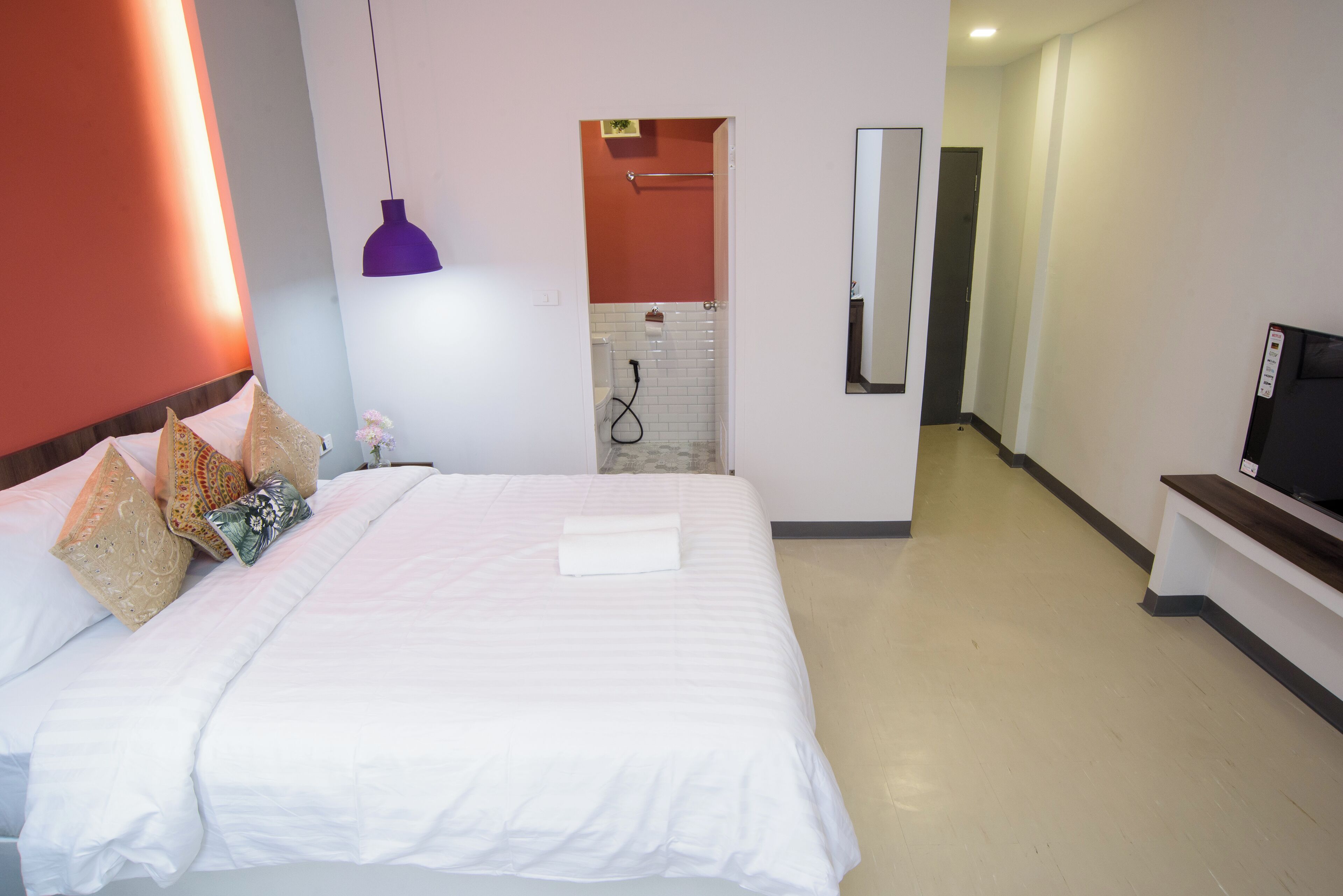 A hotel room with a large bed, a TV, a shower, and a hallway.