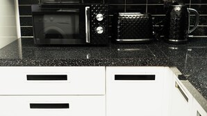 A kitchen with a black microwave, a toaster, and a coffee maker on a black countertop.