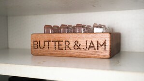A wooden block labeled "BUTTER & JAM" on a shelf.