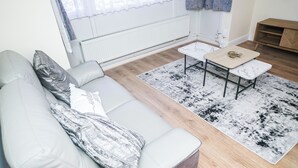 A modern living room with a grey sofa, a small coffee table, and a patterned rug.